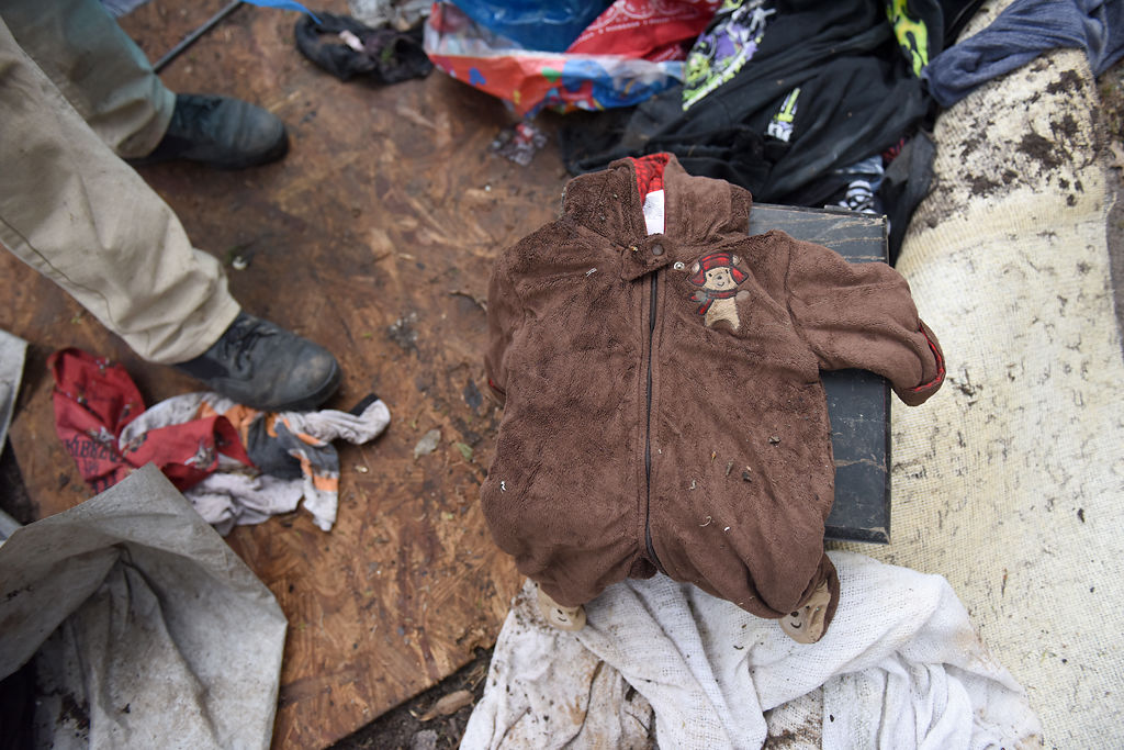 A baby outfit lies among abandoned items